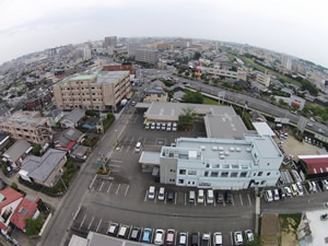 介護施設の空中からの全景。駐車場と周辺住宅地を含む